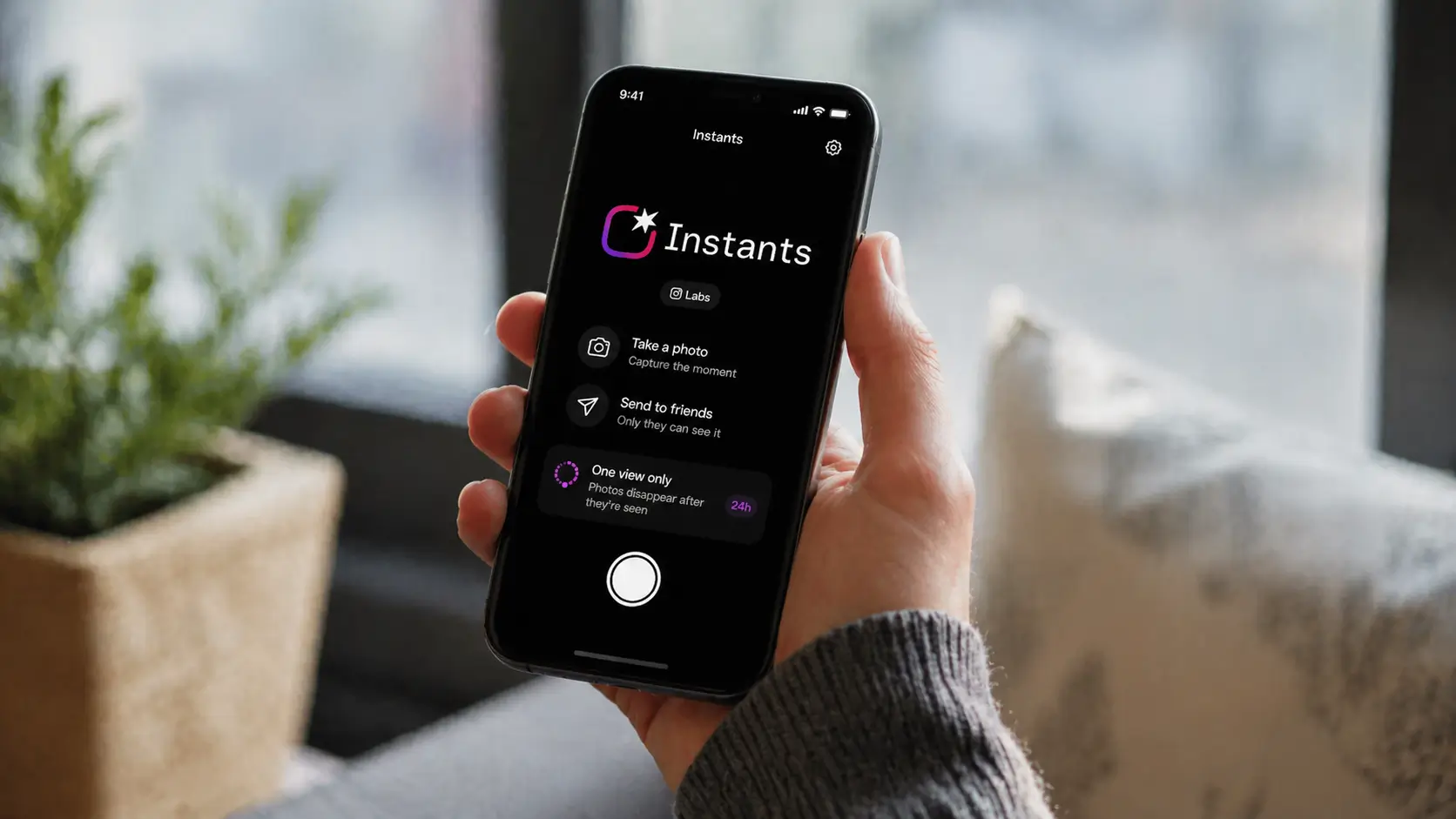 person holding smartphone with instants app meta open in bright indoor setting