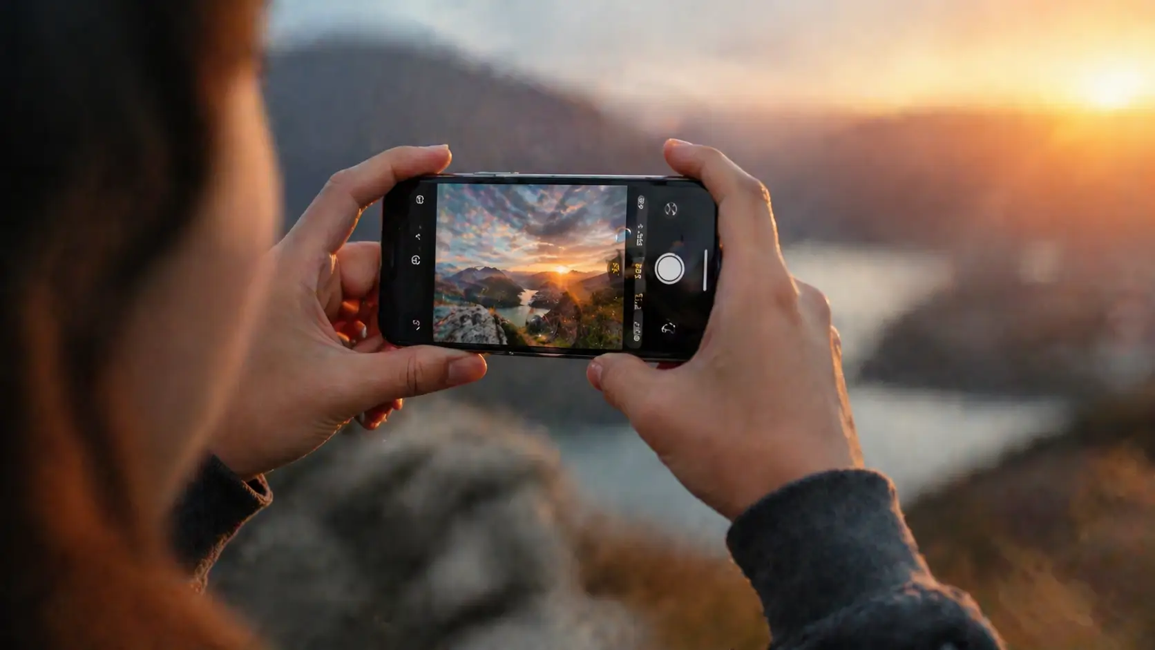 person using smartphone to capture sunset landscape showing real-world zoom photography use