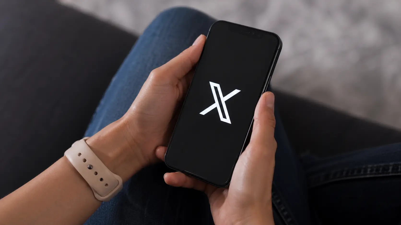 user holding smartphone with X app open on screen in real life environment